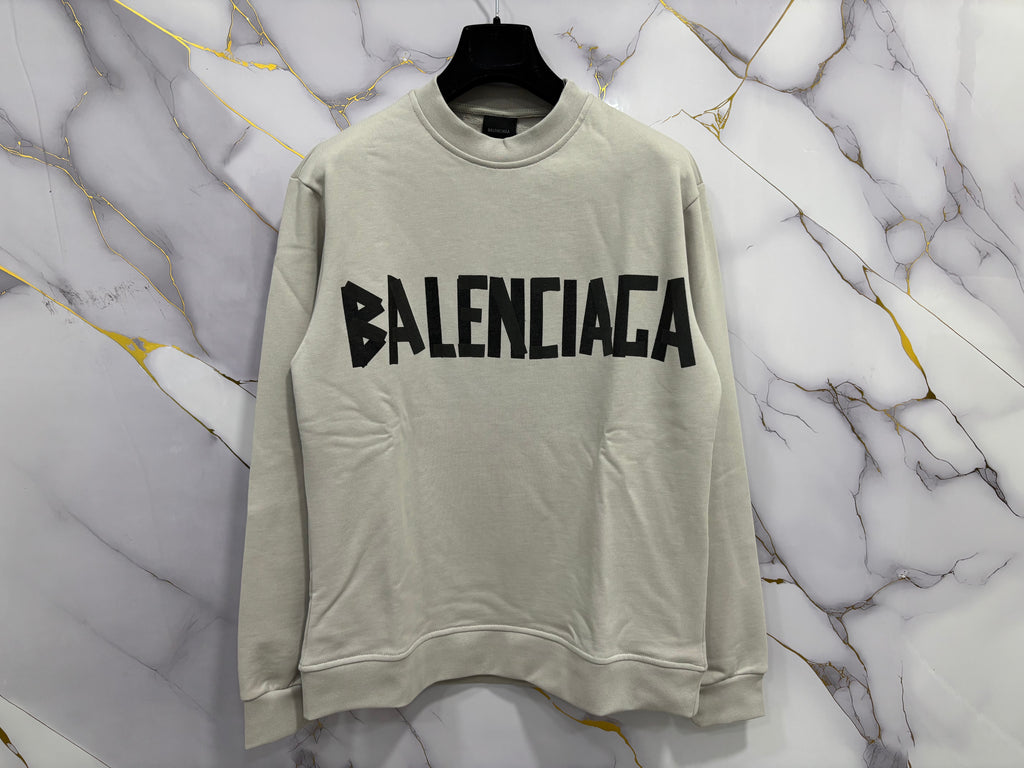 FELPA BALENCIAGA SCOCH displayed on a hanger against a marble background.