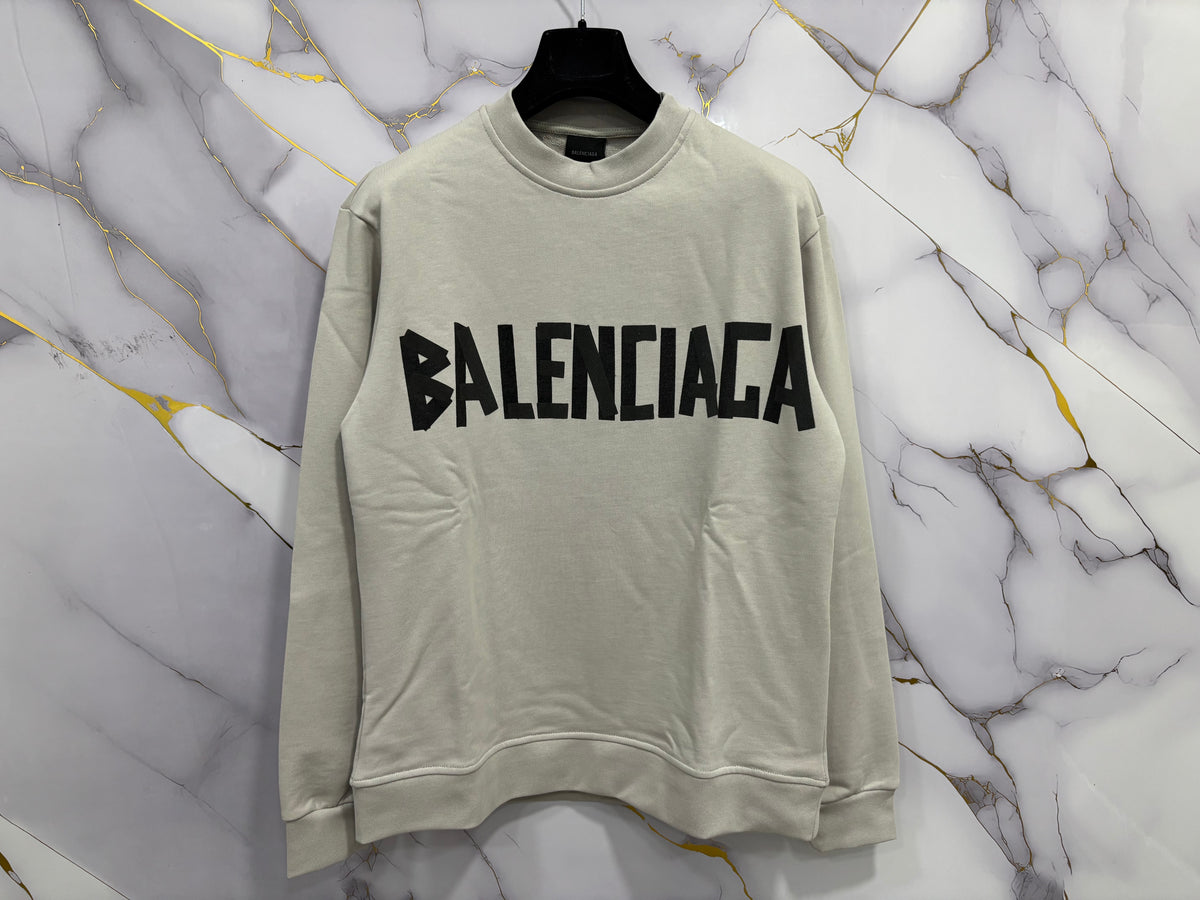 FELPA BALENCIAGA SCOCH displayed on a hanger against a marble background.