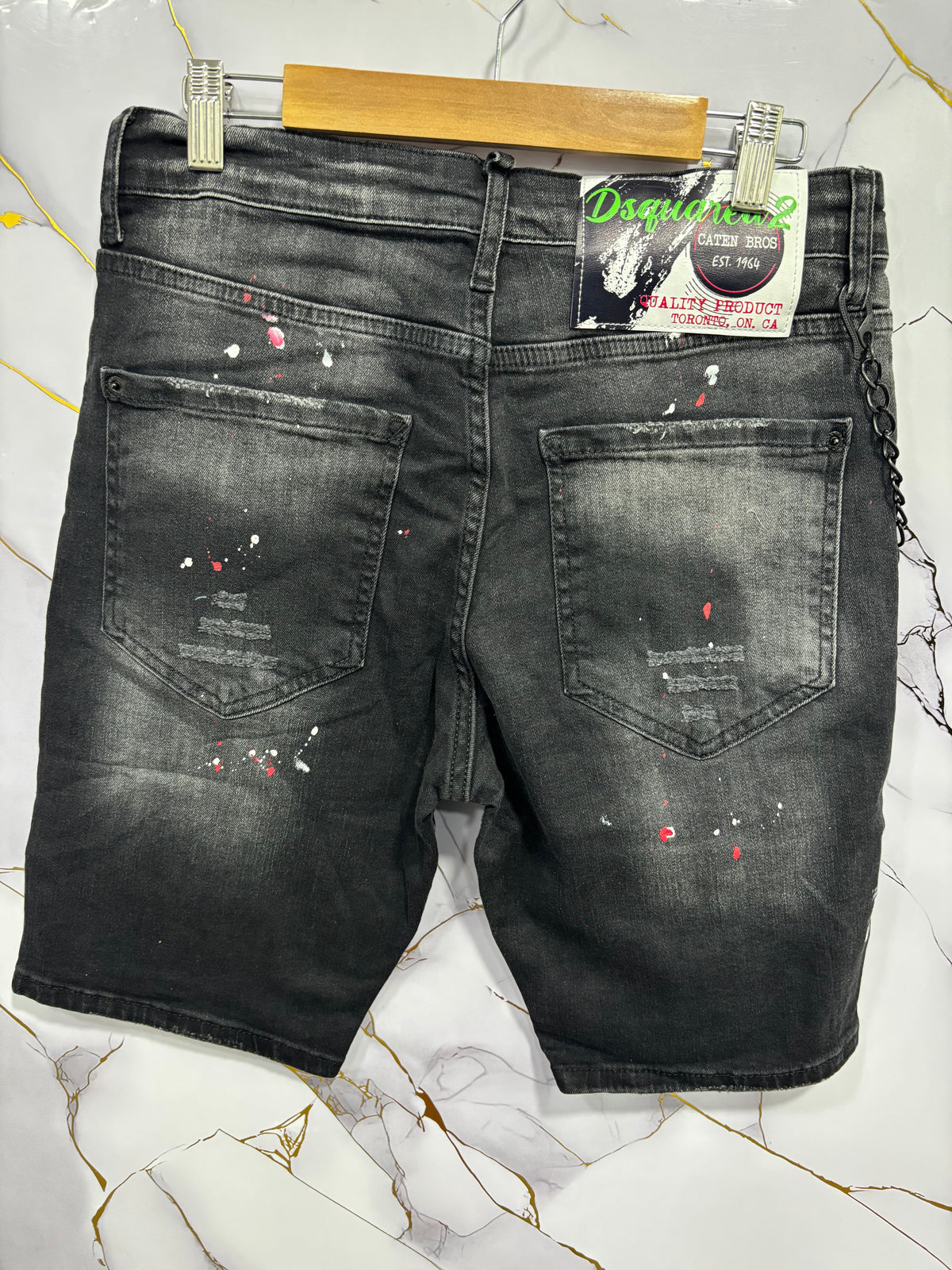 Back view of BERMUDA DSQ (CATENA) shorts showcasing distressed design and unique paint splatter details.