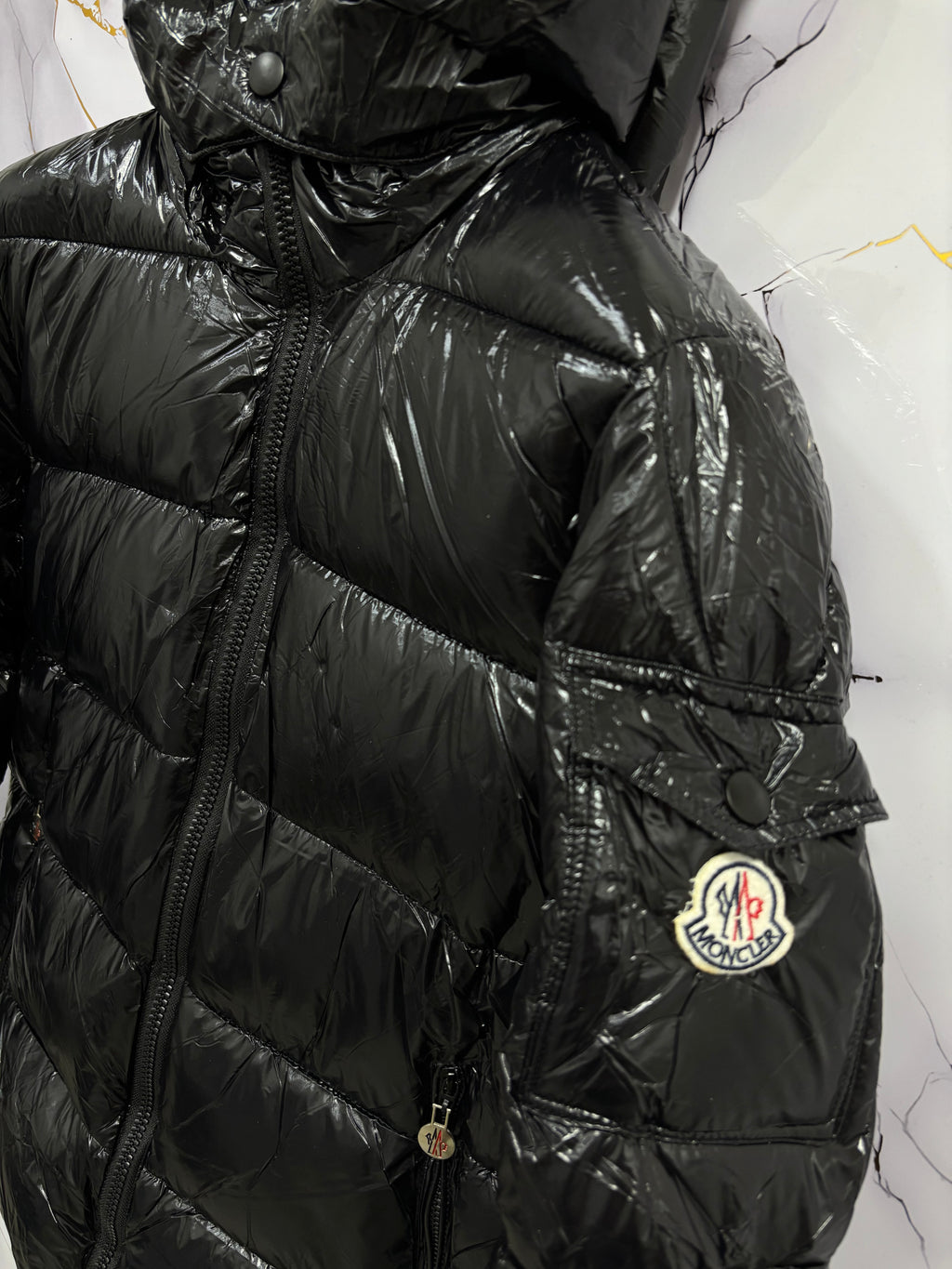 Close-up view of a sleek black GIUBBINO MONCLER with puffy design and hood, showcasing modern winter fashion.