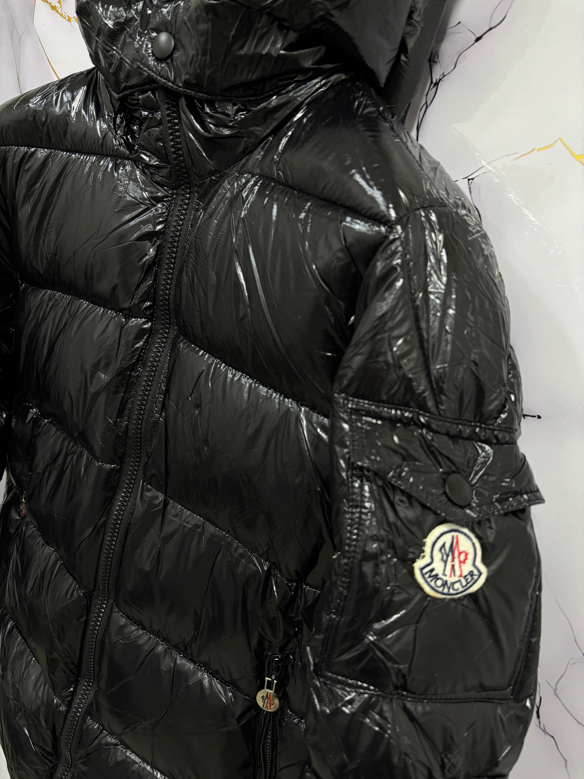 Close-up view of a sleek black GIUBBINO MONCLER with puffy design and hood, showcasing modern winter fashion.