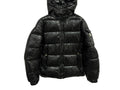 GIUBBINO MONCLER in glossy black on a marble background, showcasing its stylish design and warm insulation.