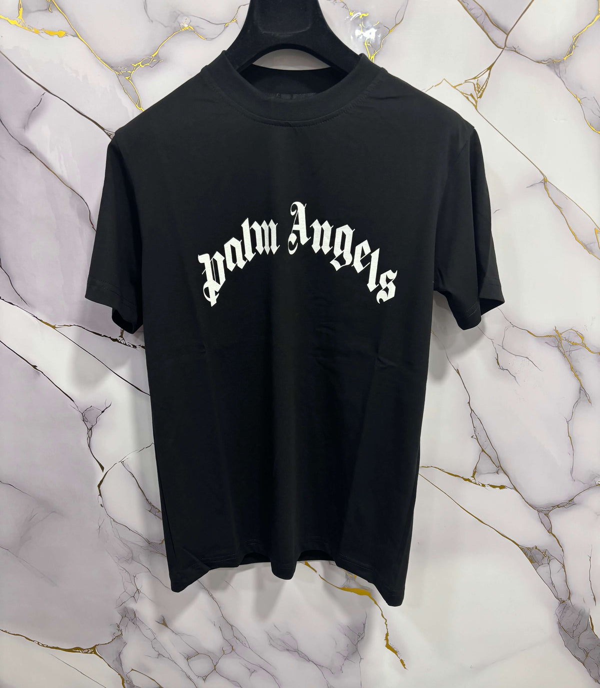 T-SHIRT PALM CURVATA displayed on a hanger against a stylish marble background, showcasing its unique design.
